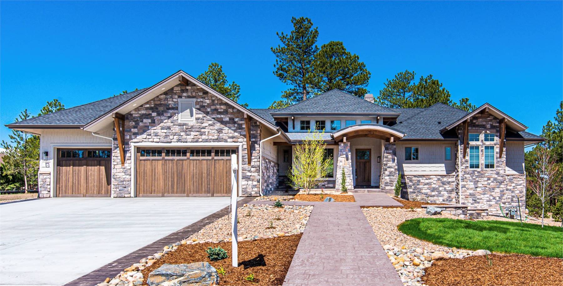 Craftsman-style ranch home with stone and siding exterior, three-car garage, and covered entry.